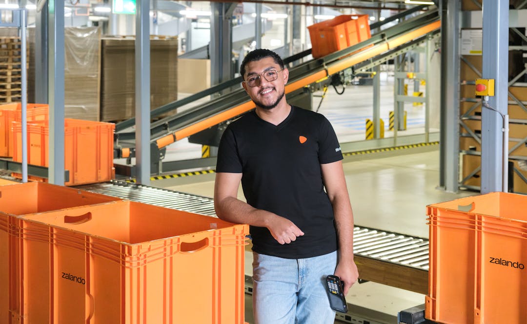A person standing next to an orange container at a warehouse
