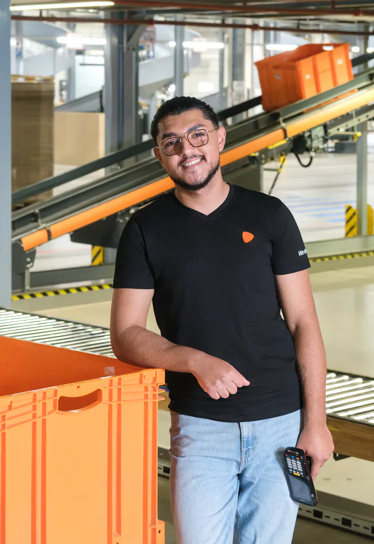 A person standing next to an orange container at a warehouse