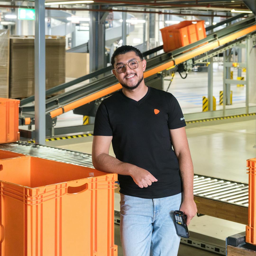 A person standing next to an orange container at a warehouse