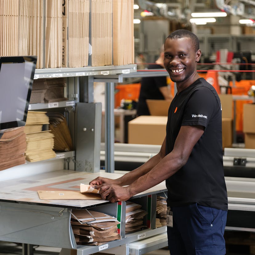 A person standing at a work station in a warehouse 