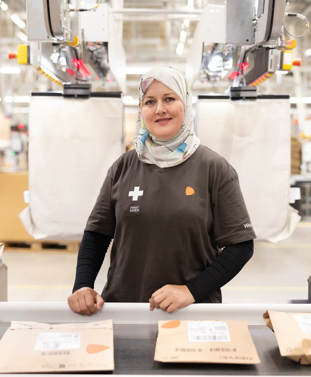 A woman standing at a logistics centre before packages on a conveyor belt.