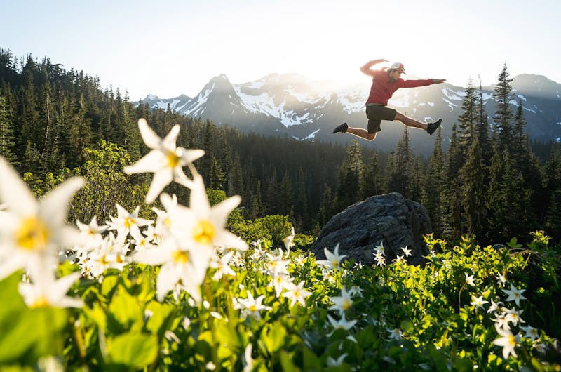 Man jumping in a field with mountains in the background