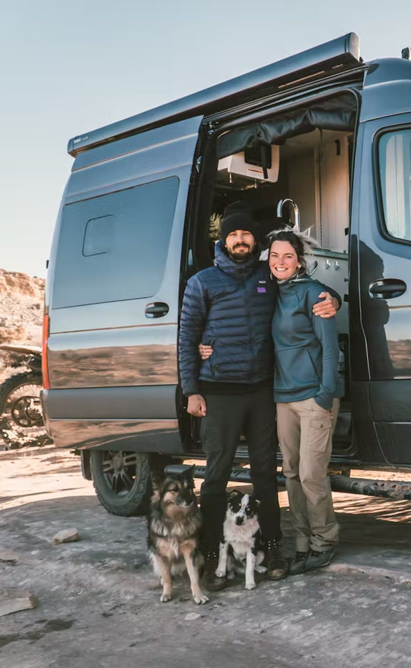 Couple standing next to Sanctuary RV with their dogs