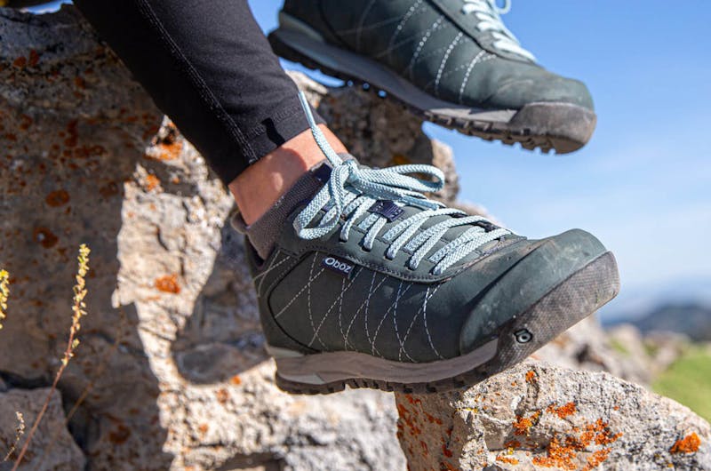 A close up view of hiking sneakers on someone who is sitting on rocks