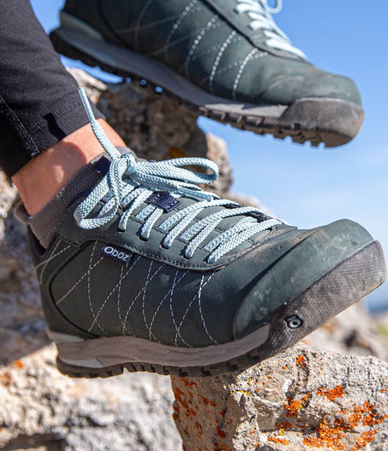 A close up view of hiking sneakers on someone who is sitting on rocks