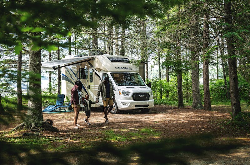 Family walking together outside of RV at a campsite.