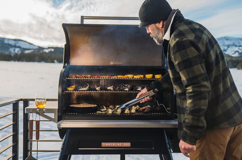 A man grilling vegetables in the winter on a Traeger