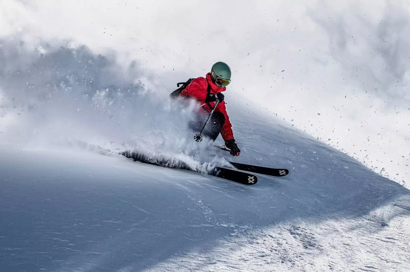Man skiing down a mountain using Volkl skis