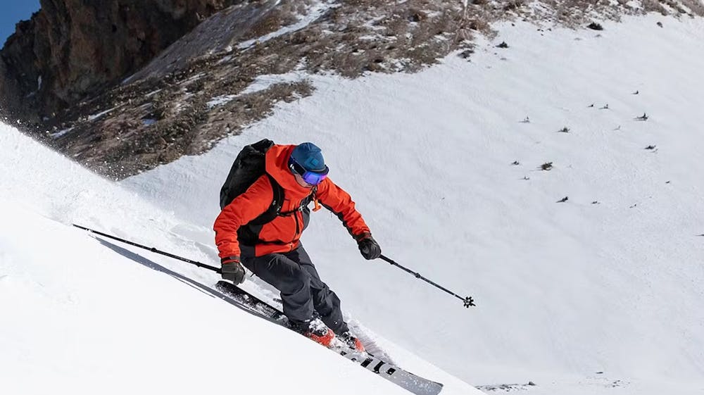 Person in red snow coat skiing down a mountain