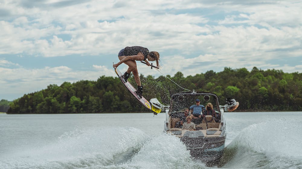 Person wakeboarding performing an aerial trick in front of a MasterCraft boat