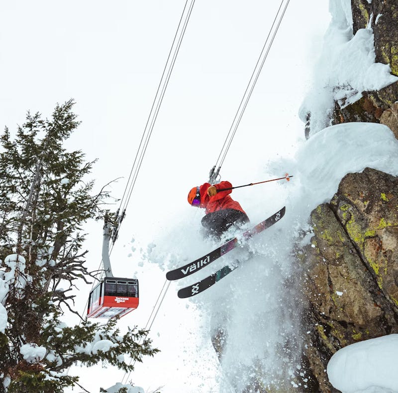 Skier ripping through snow with Jackson Hole Aerial Tram in background