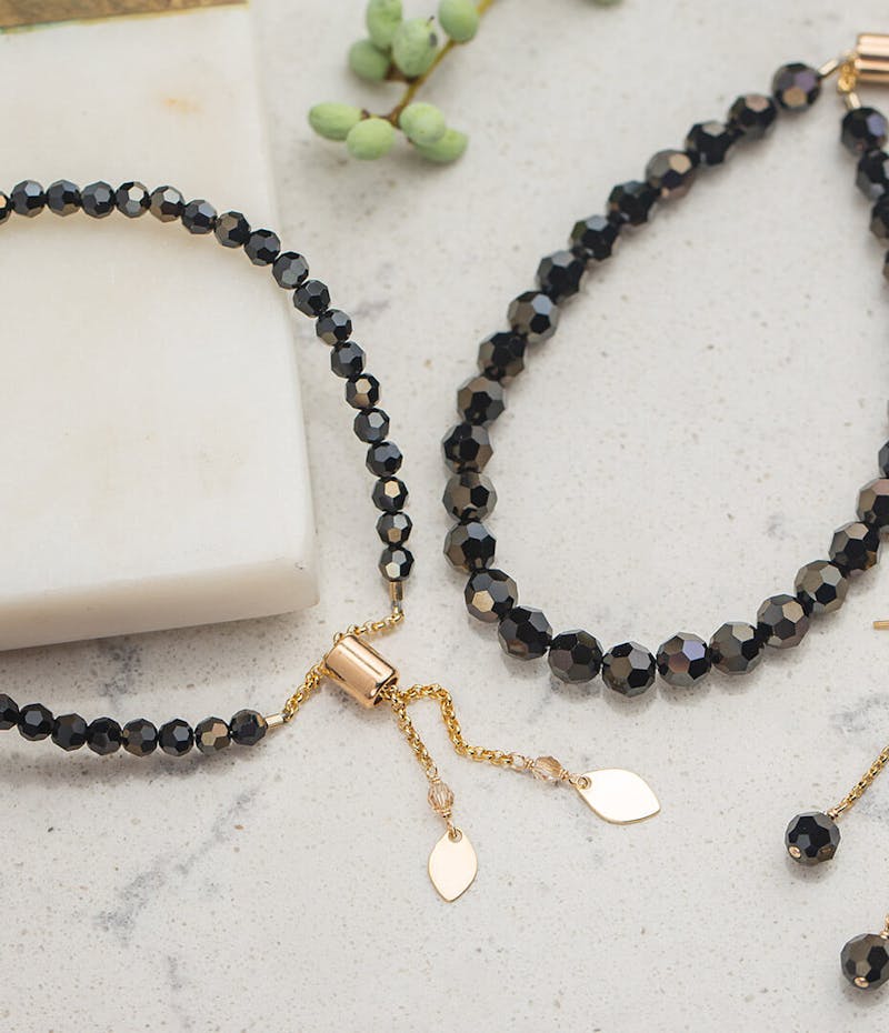 Black beaded jewelry laying on a stone countertop