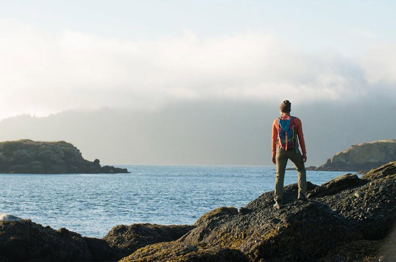 Woman standing on rocks looking at the ocean