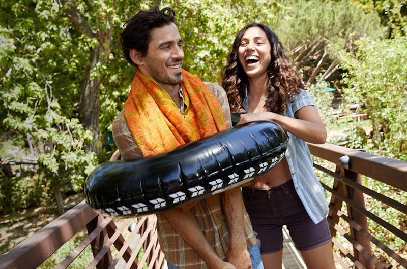 Man wearing float and woman laughing while outdoors
