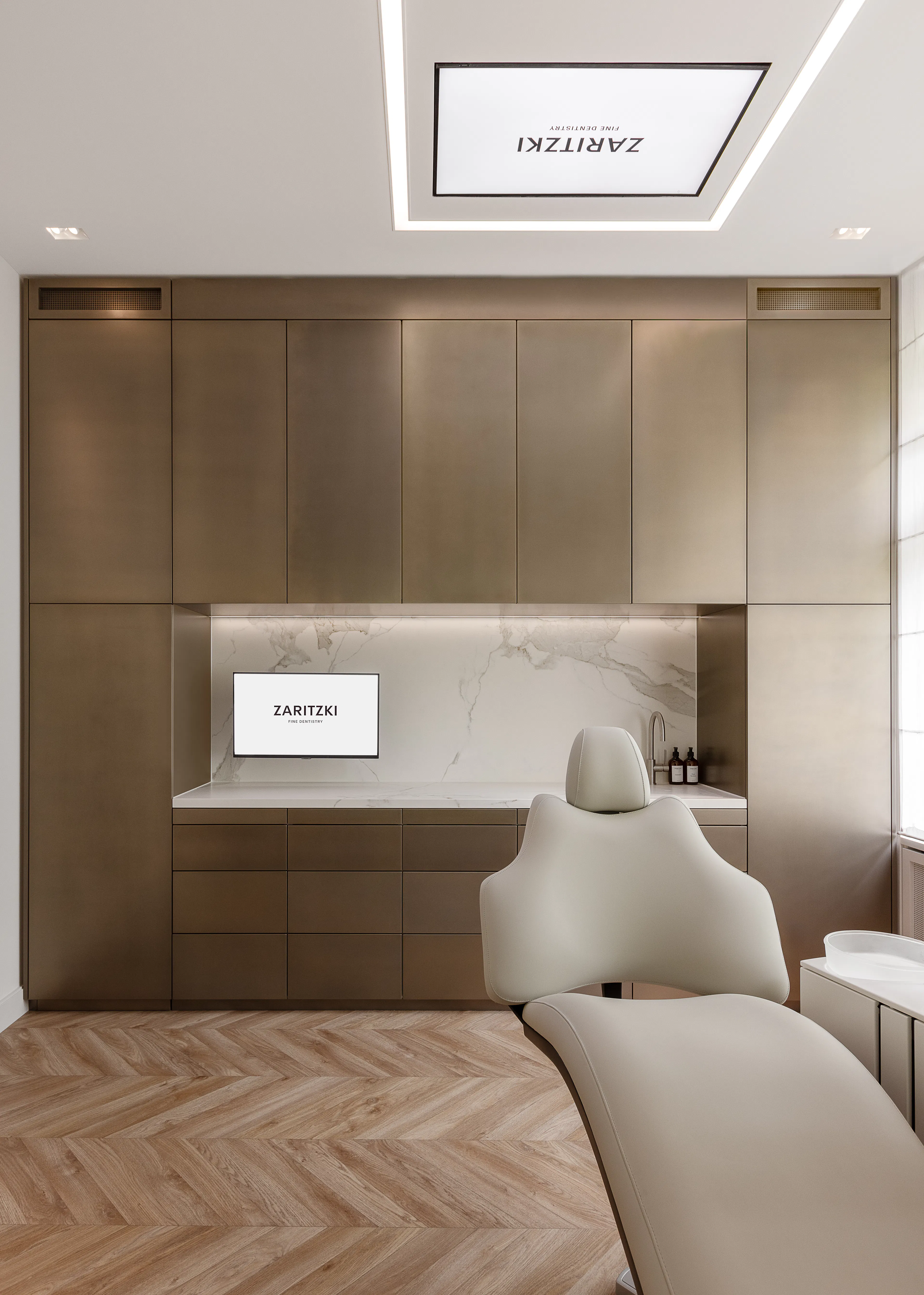 Behandlungszimmer mit Deckenbildschirm, Bronzewand und hellem Behandlungsstuhl