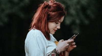 Mulher segurando celular com TIM pré pago na mão.