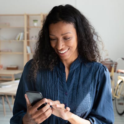 mulher sorrindo digitando em seu celular