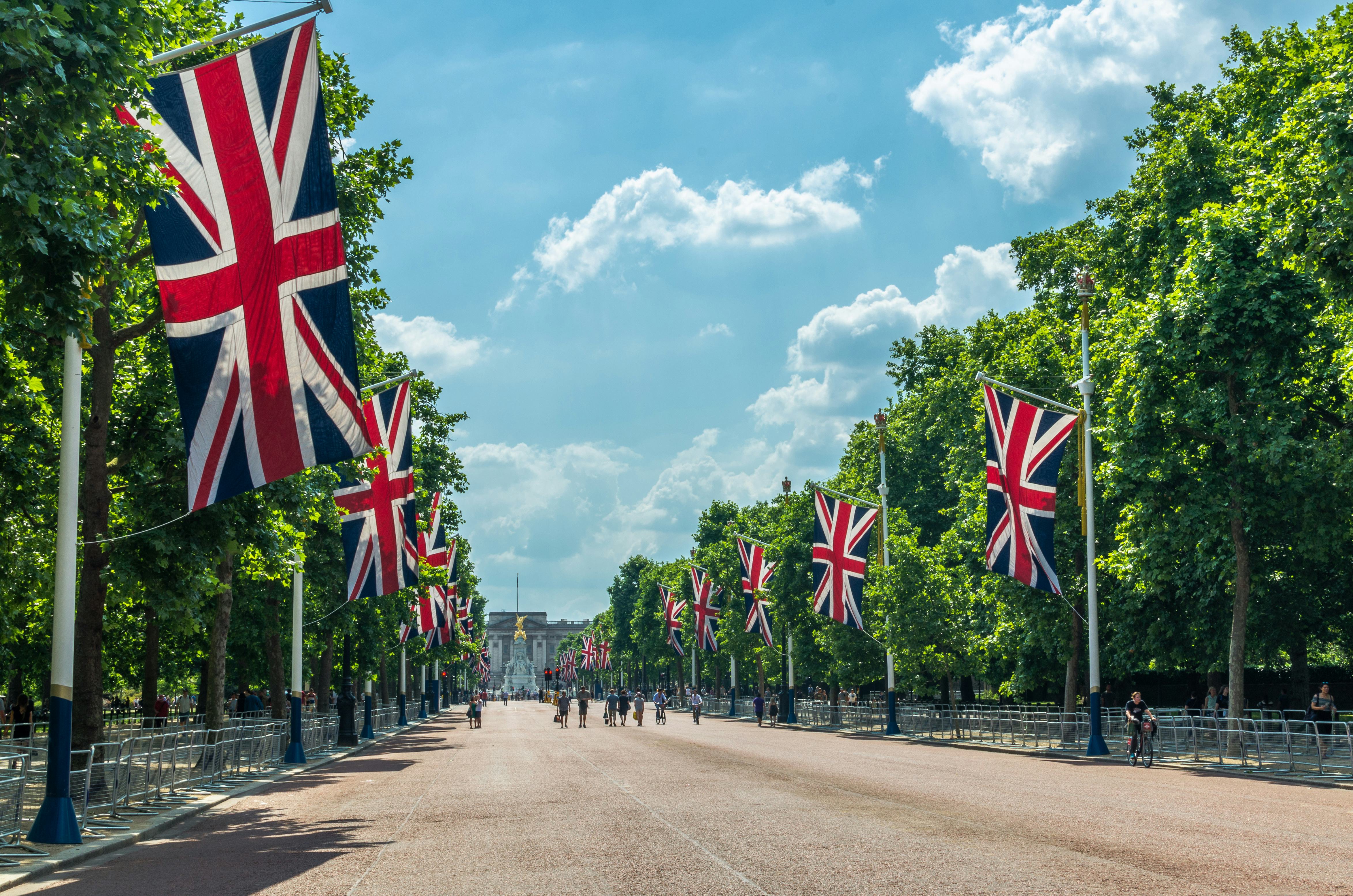 British flags hanging from flag poles on The Mall in London heading towards Buckingham Palace.