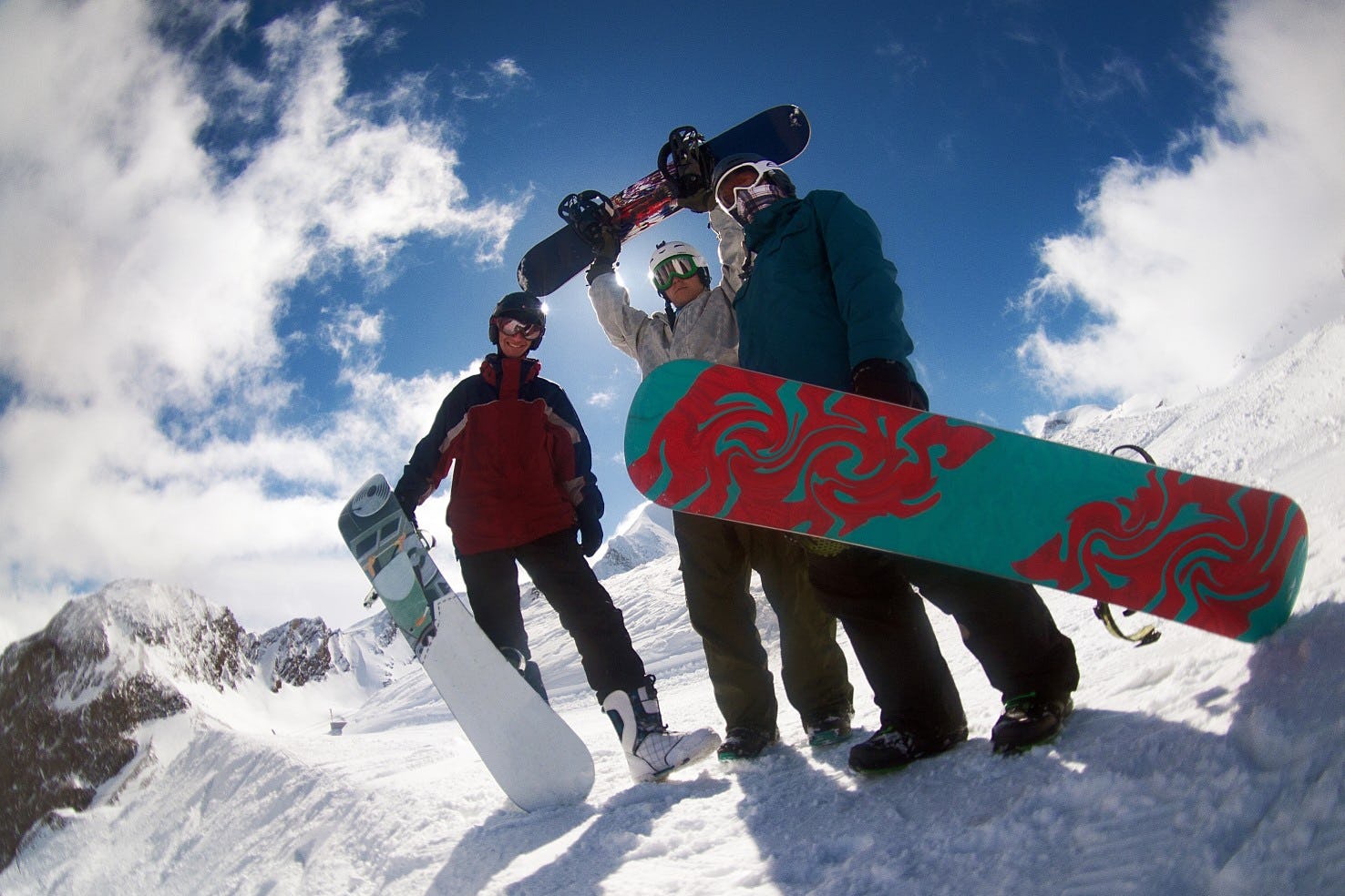 Group of 3 snowboarders posing in front of some fresh snow