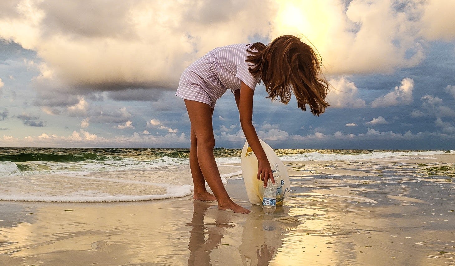 Small girl cleaning up trash on the shores of a beach