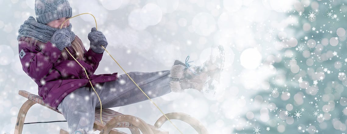 child on wooden sled in the snow