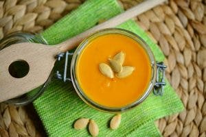 jar of pumkin soup with 4 pumpkin seeds added as garnish