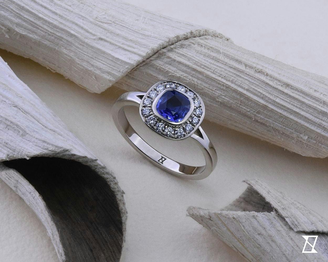 Cushion cut sapphire with diamond halo in white 14k gold.