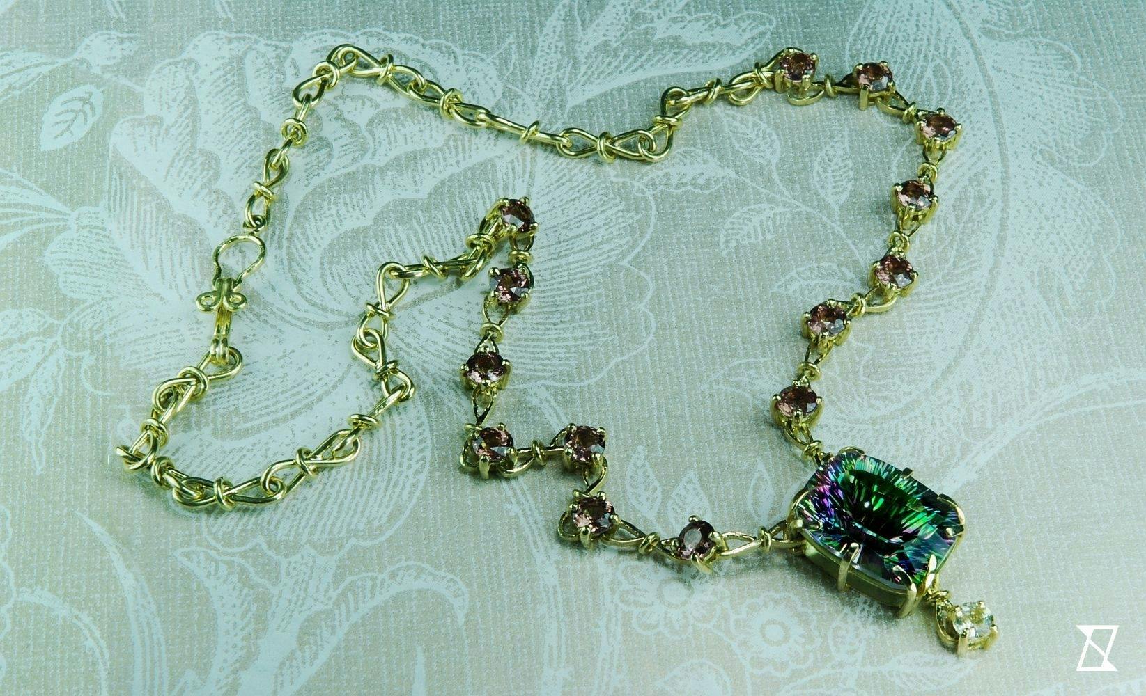 Green gold necklace featuring rainbow topaz and Malaya garnets. 