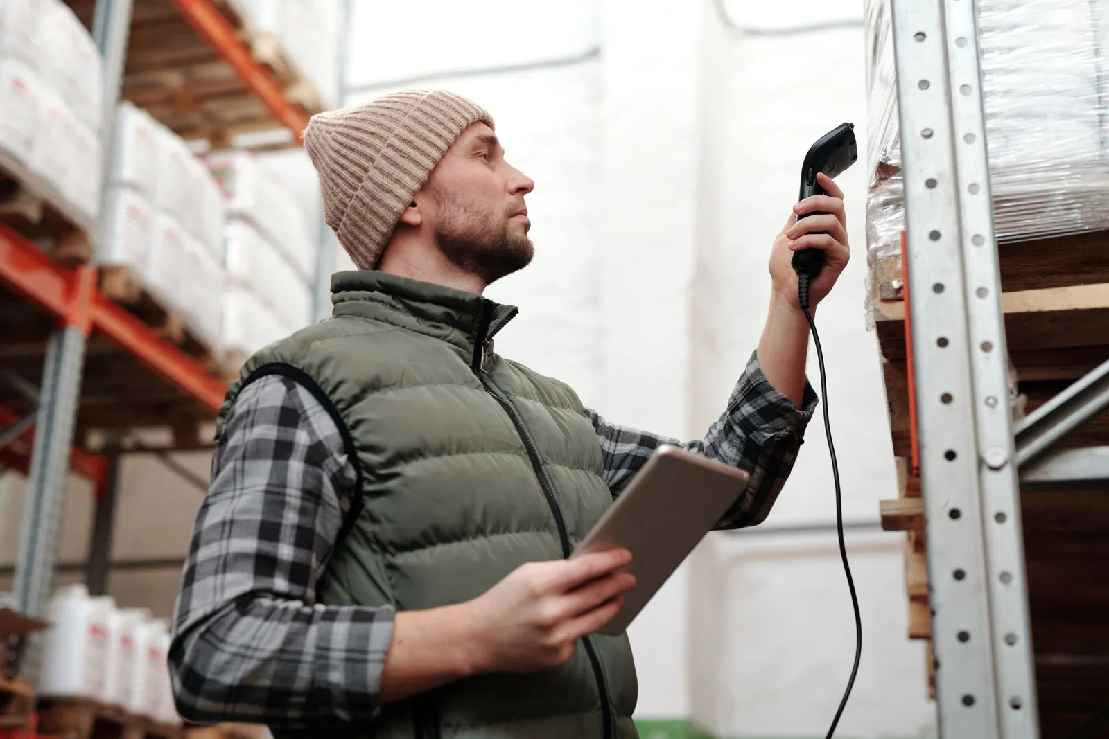 Warehouse worker scanning a barcode during order picking, the moment where warehouse logistics must hand off cleanly to automated shipping decisions