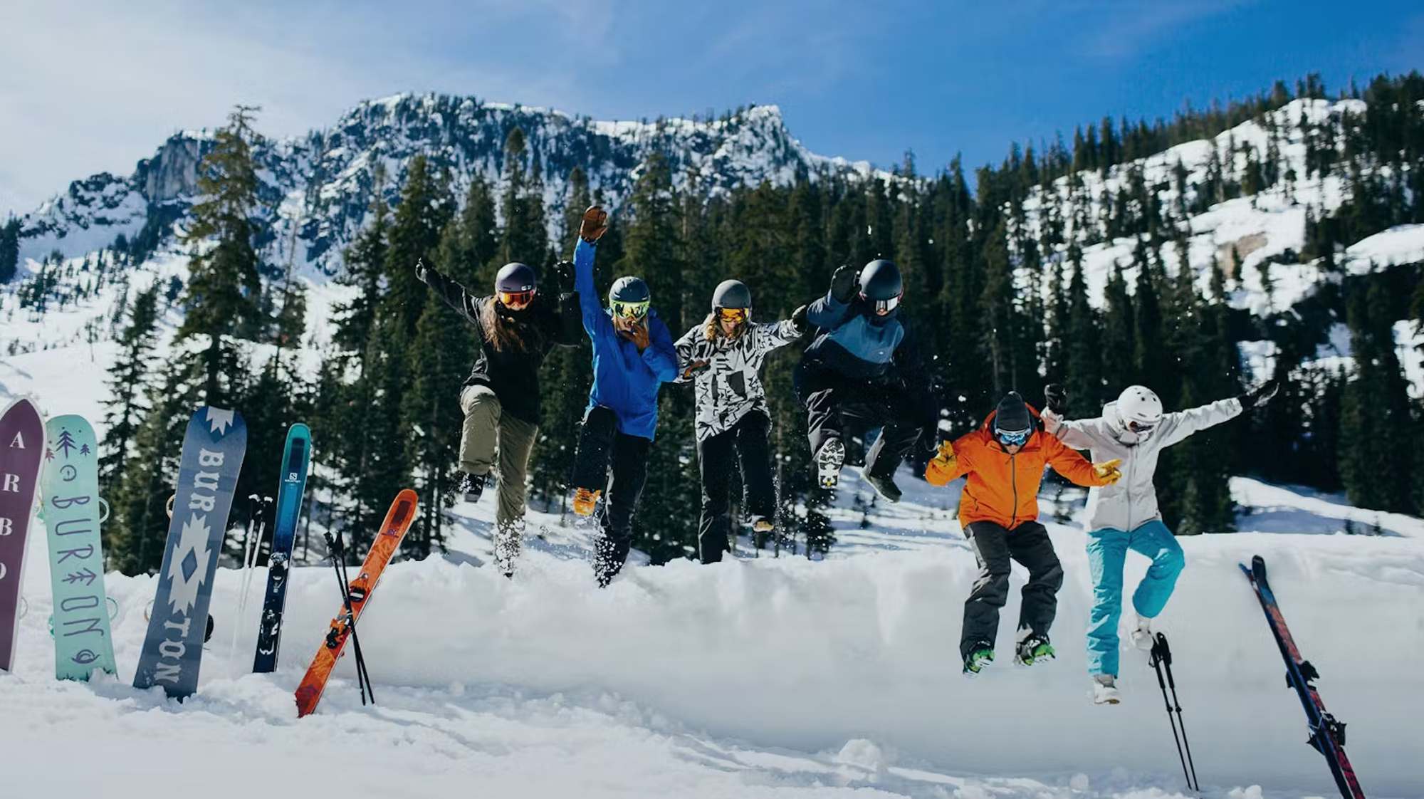 Several people in snow gear and  jumping into snow