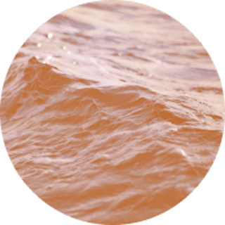 Circle image of the ocean with an orange coloured filter over the top