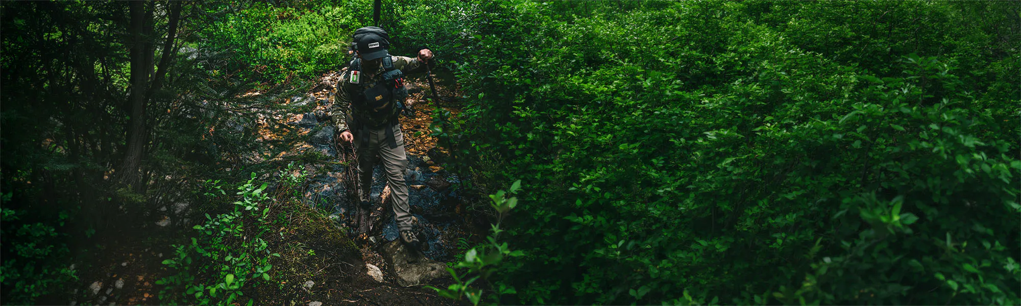 hunter hiking through dense forest, with ZOLEO satellite communicator attached to their backpack