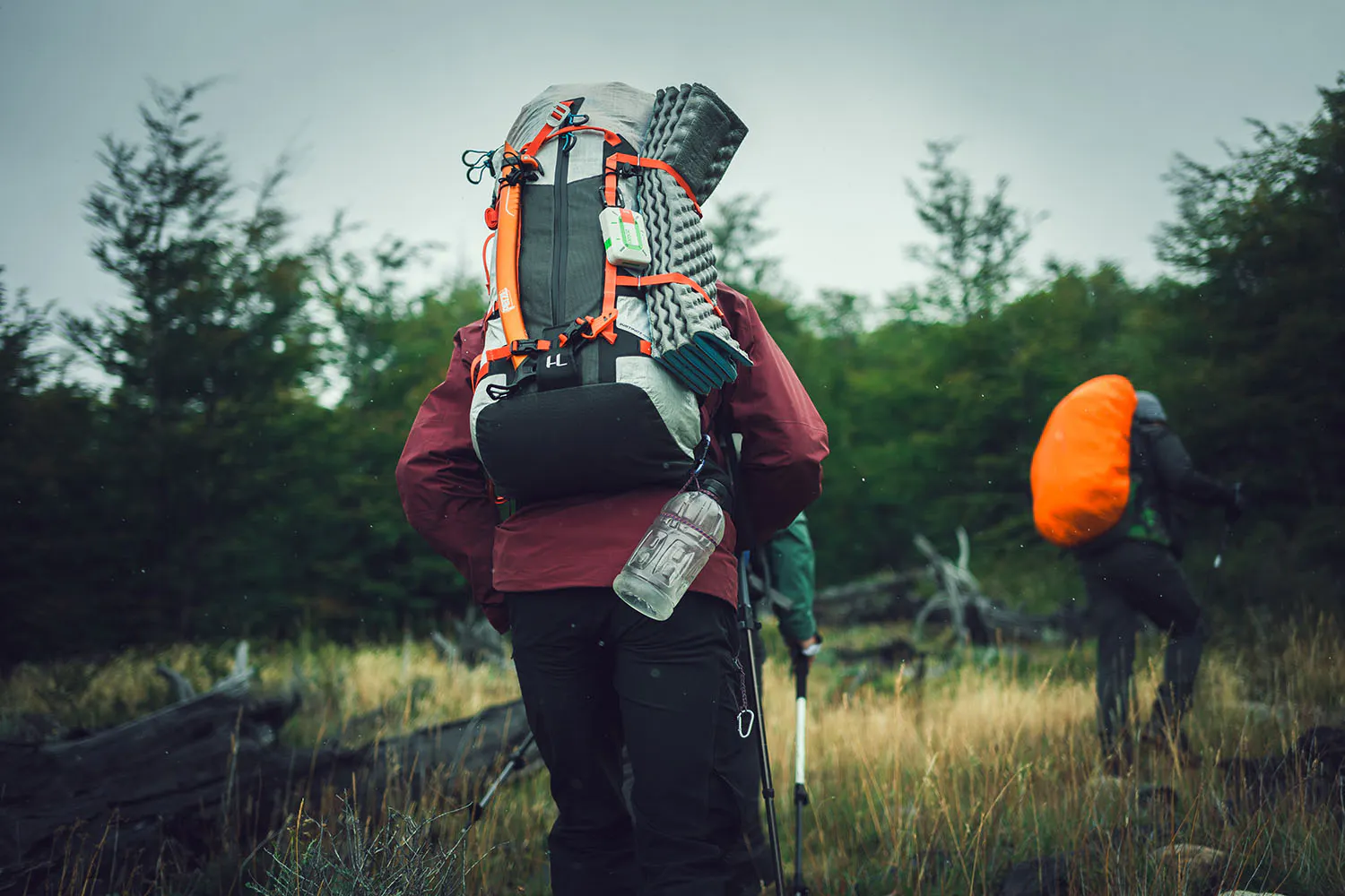 hikers with backpacks in the forest, ZOLEO device hanging on the bag