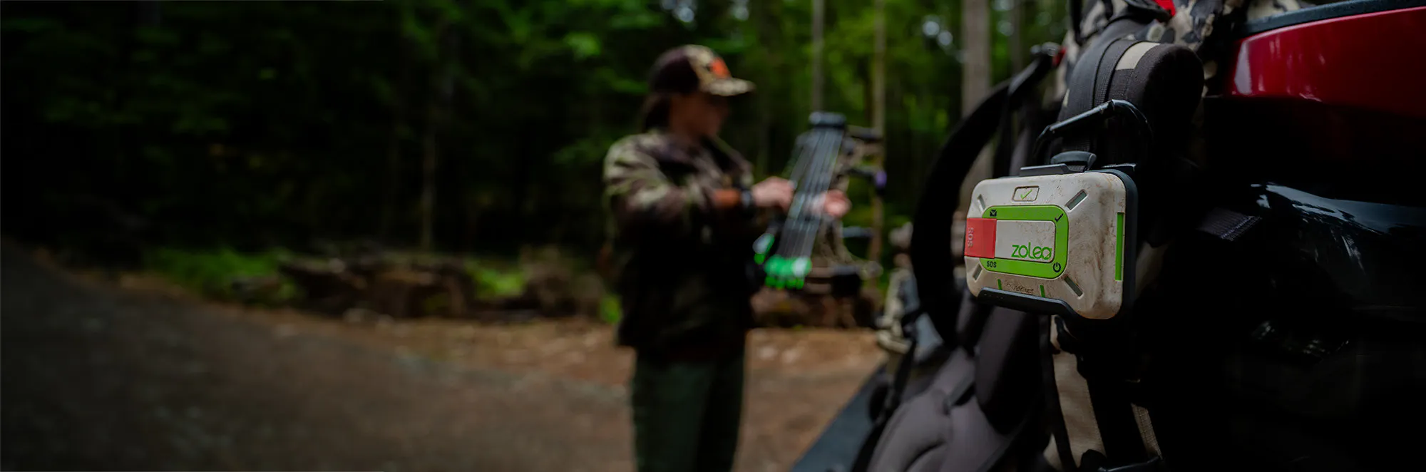 a hunter in the wilderness adjusting equipment, ZOLEO satellite device in sight