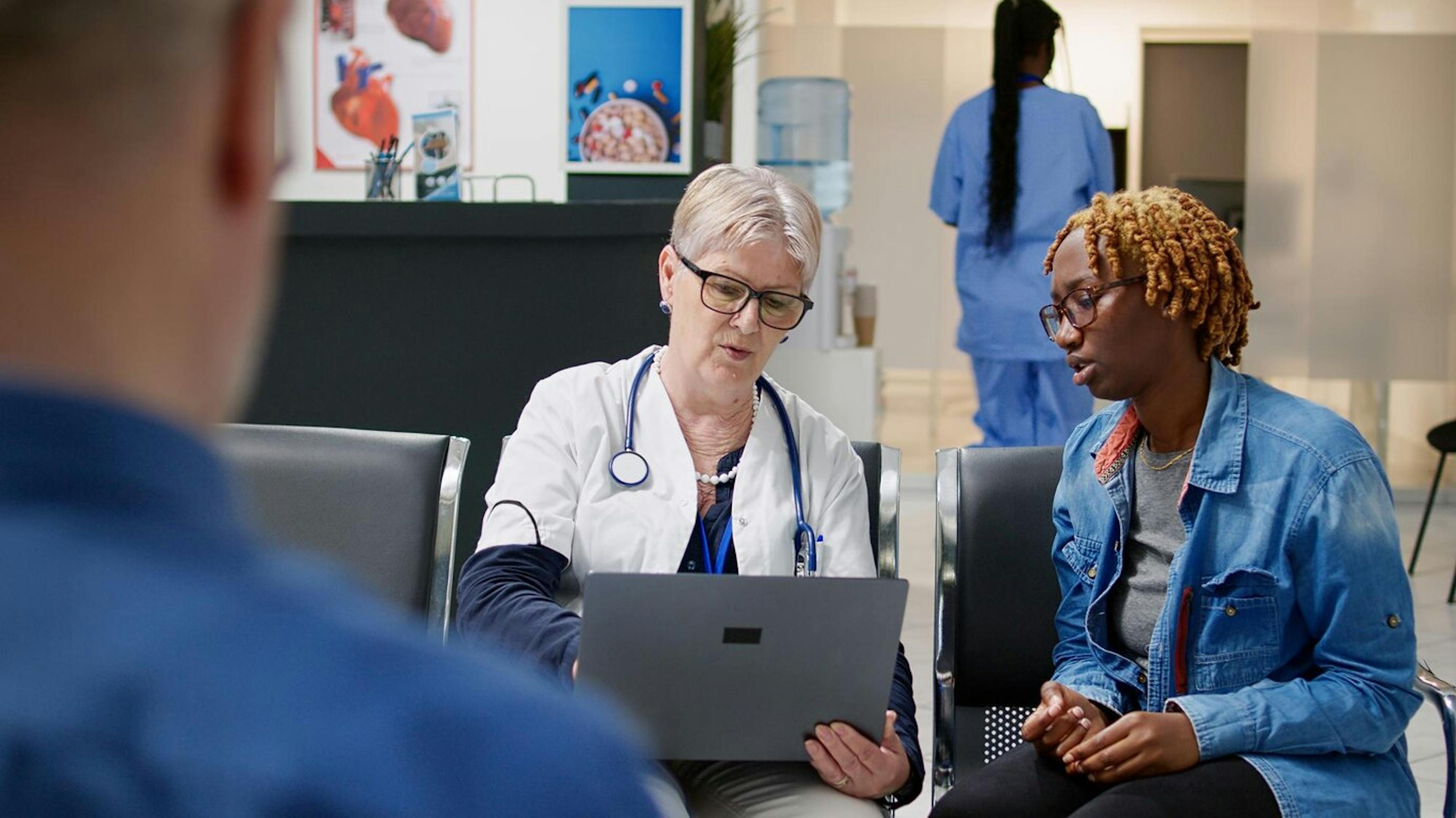 senior-medic-showing-diagnosis-on-laptop-to-sick-patient