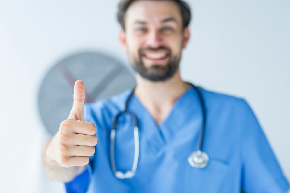 blurred-doctor-showing-thumb-up-gesture