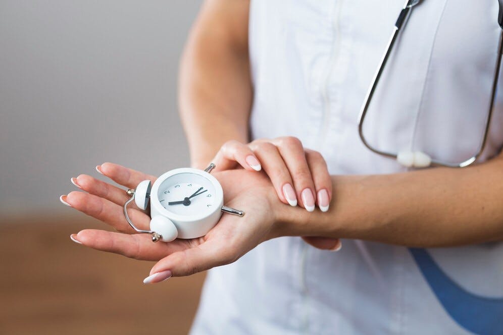 female-doctor-hands-holding-little-clock