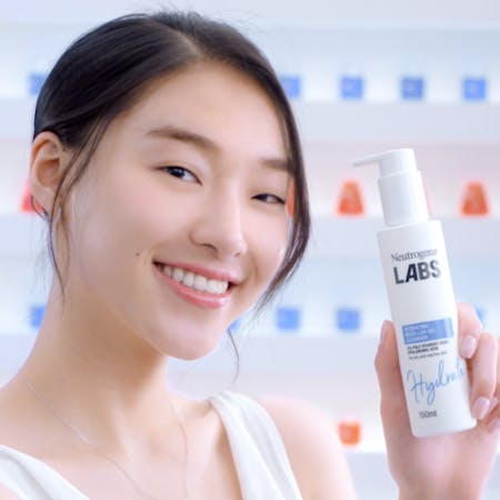 A woman smiling holding a Neutrogena Labs pack