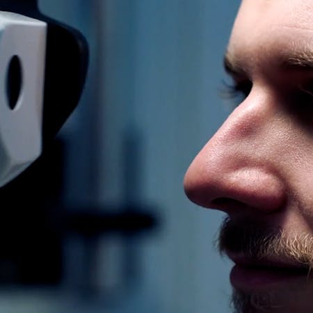 Man looking into the phoropter during an eye exam